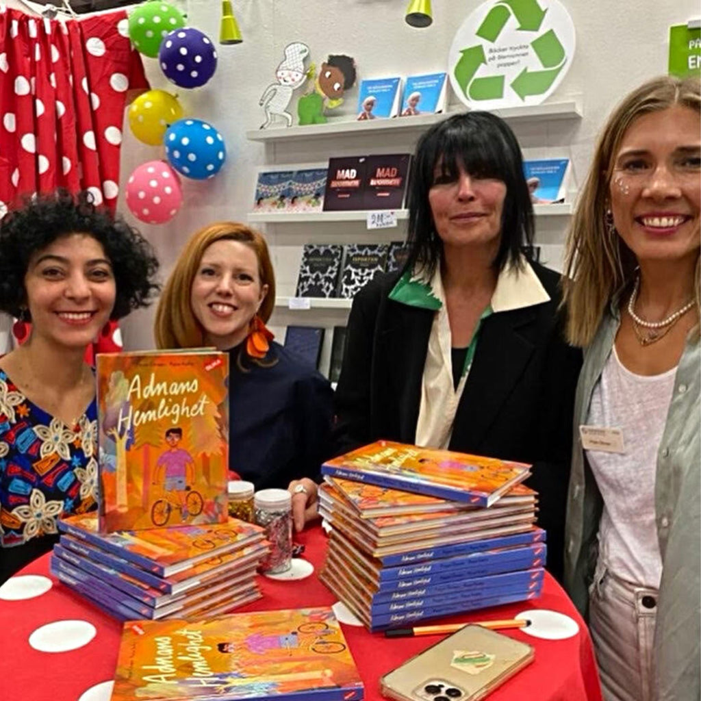 Författaren Peppe Öhman och illustratören Rana Kadry tillsammans med Röda Korsets representanter i OLIKAs monter på Bokmässan 2022. I mitten finns boken Adnans hemlighet.  
