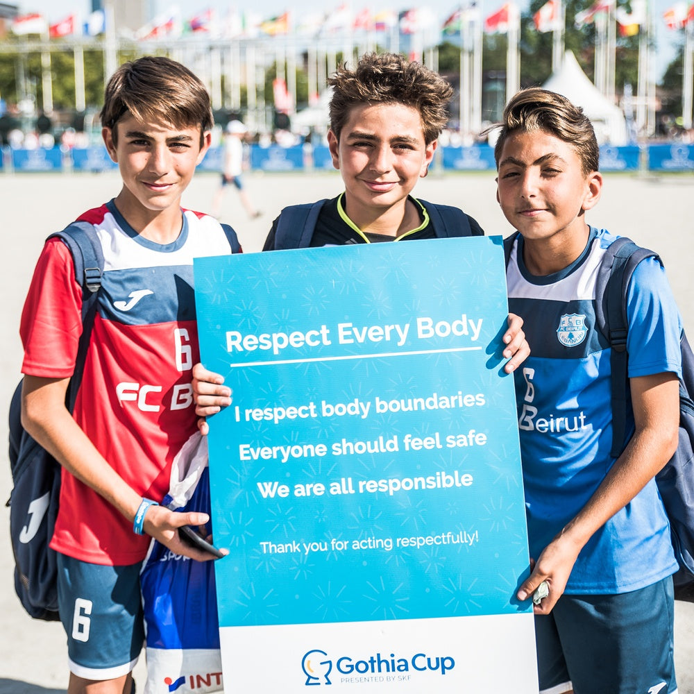 Tre unga pojkar på Gothia Cup håller upp en skylt om "Respect Every Body"