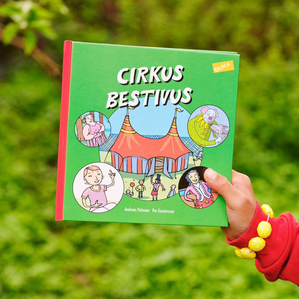 En hand som håller upp framsidan av Cirkus Bestivus - Bilderbok 3-6 år - OLIKA förlag - Författare: Andreas Palmaer - Illustratör: Per Gustavsson