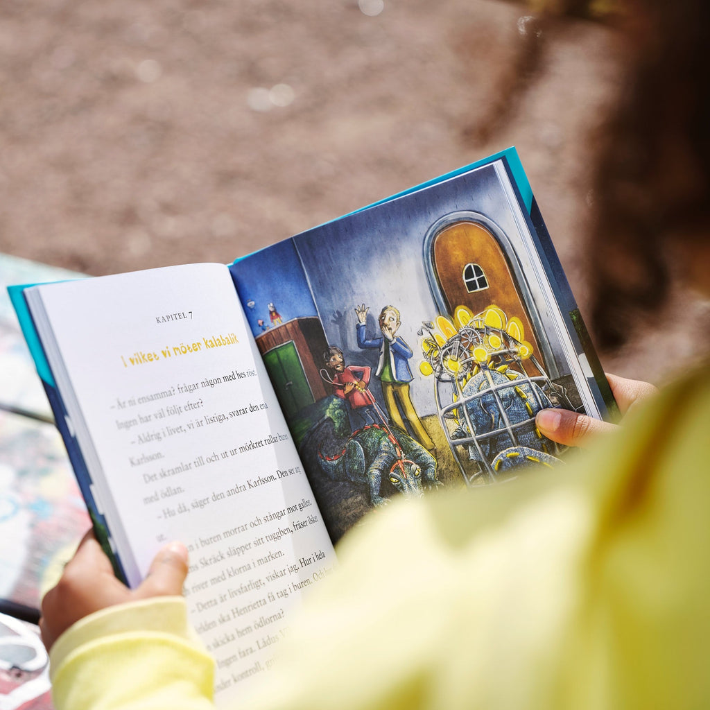 Ett barn tittar ner på en av illustrationerna i De vilda & den mystiska tidsmaskinen - 6-9 år - OLIKA förlag - Författare: Cecilia Rihs - Illustratör: Anna Westin