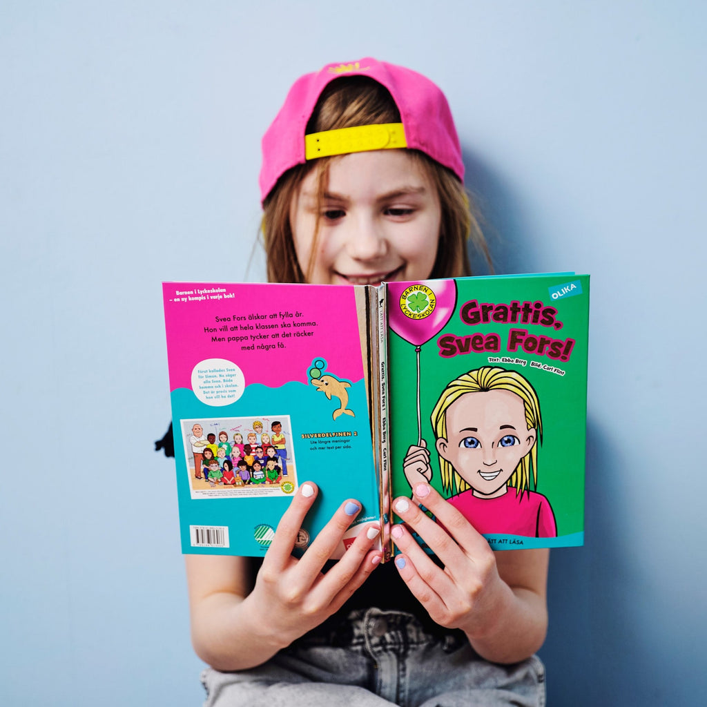 Ett leende barn i rosa keps läser i Grattis, Svea Fors! - Barnen i Lyckeskolan - Lättläst 6-9 år - OLIKA förlag - Författare: Ebba Berg Illustratör: Carl Flint