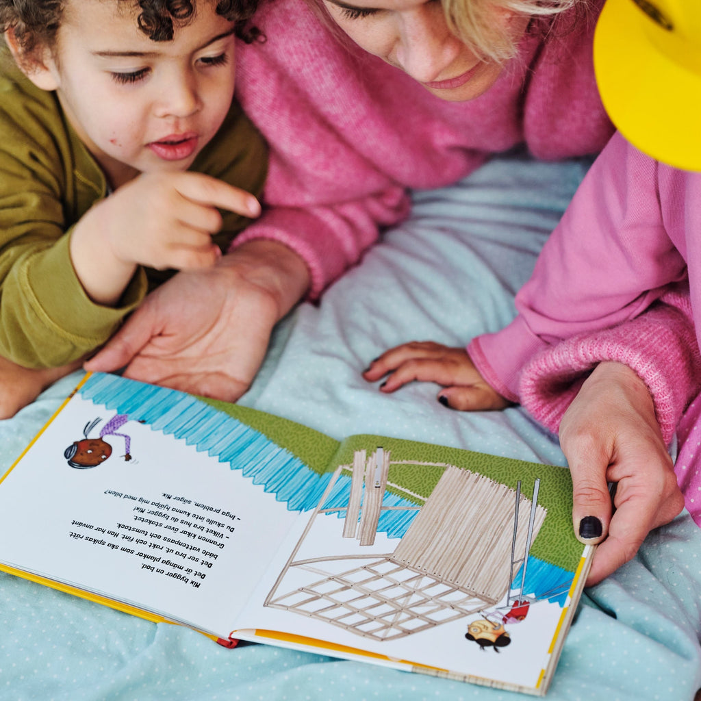 En vuxen och två barn tittar på bilderna i Mix bygger - Bilderbok 1-3 år - OLIKA förlag - Författare: Malin Lilja - Illustratör: Matilda Salmén