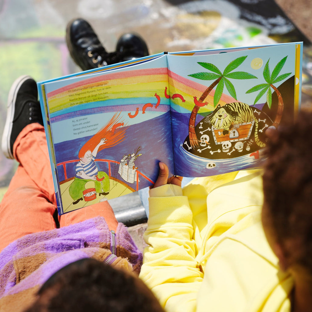 Två barn tittar ner på ett färgglatt uppslag i Piraterna & regnbågsskatten - Bilderbok 3-6 år - OLIKA förlag - Författare: Karin Frimodig och Sara Berg - Illustratör: Maria Poll