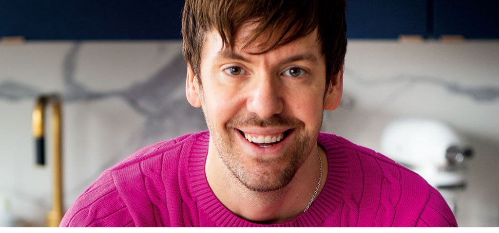 Ett färgfoto av kokboksförfattaren Mattias Kristiansson som står i ett kök och ler in i kameran