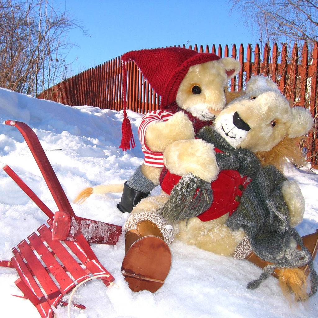 Ett lejon har ramlat av sin kälke i snön och får hjälp upp av en nalle