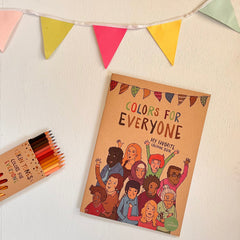 Målarboken Colors For Everyone syns på vit träyta med ett paket färgpennor och en färgglad vimpelgirlang