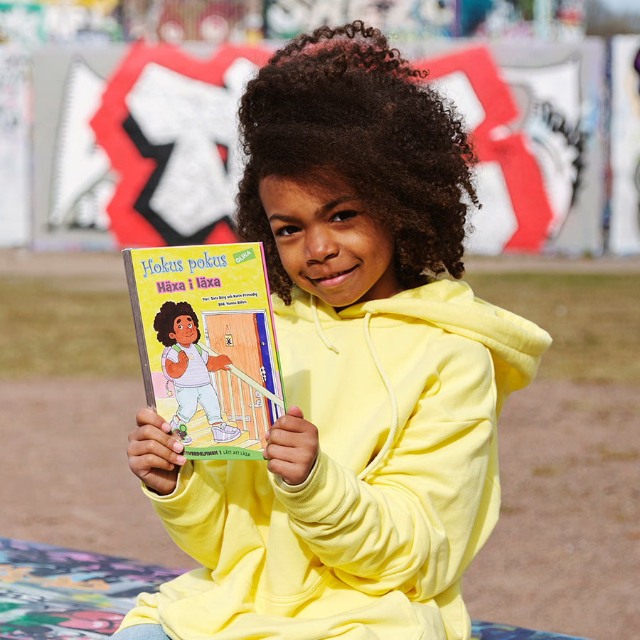 Ett barn håller upp boken Hokus pokus: Häxa i läxa.
