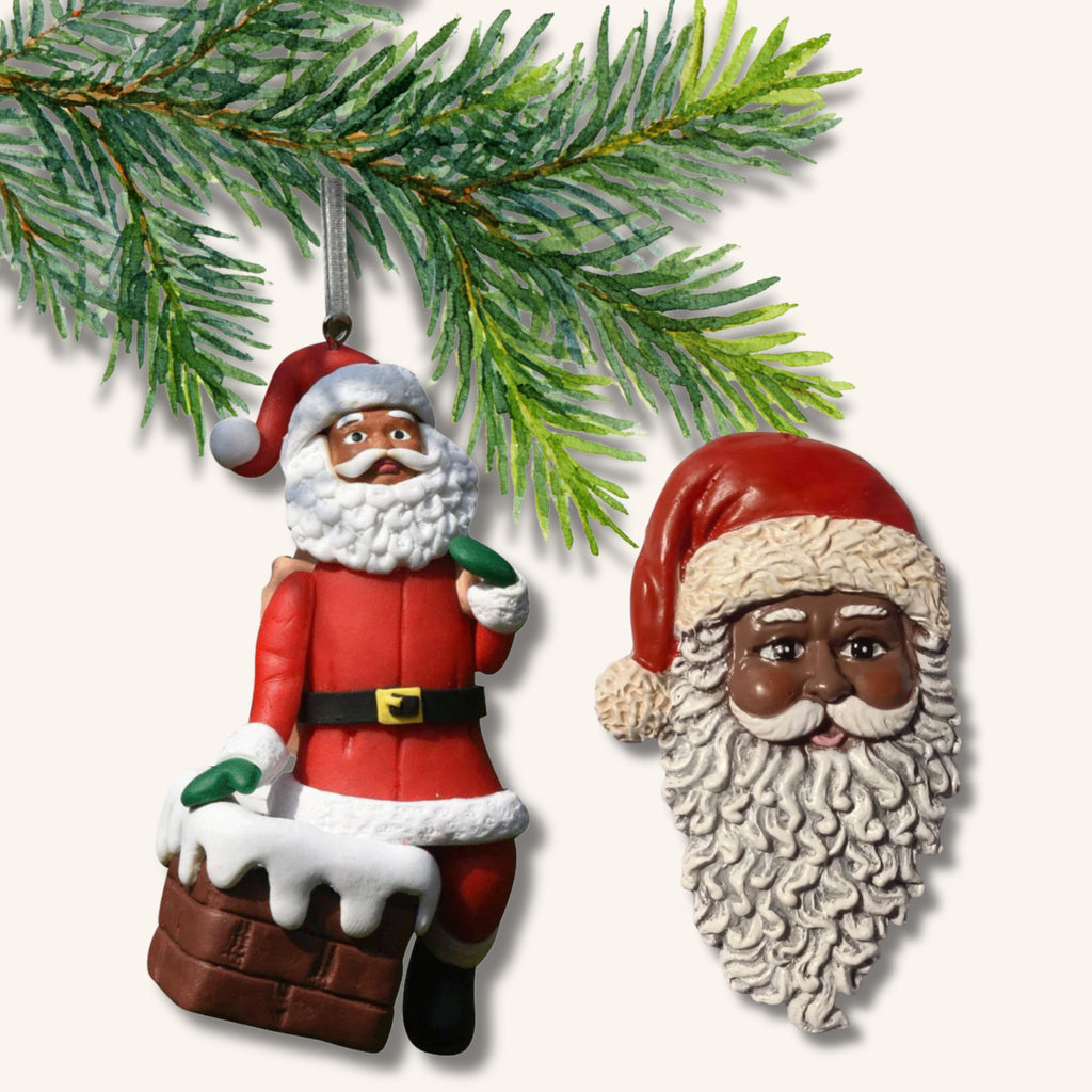 Två juldekorationer föreställande tomtar med brun hudfärg tillsammans med en grankvist.