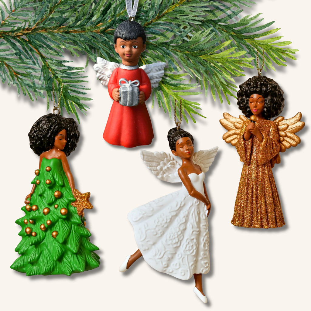 Fyra inkluderande ängel-dekorationer med brun hudfärg – barn, ballerina, sångerska och kvinna i julgransklänning – upphängda på en grankvist.