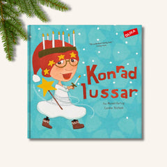 Bilderboken Konrad lussar på vit yta. Ovanför boken i det vänstra hörnet syns en grön grangren
