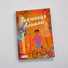 Kapitelboken Adnans hemlighet (på ukrainska) ligger på vit träyta
