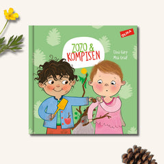 Bilderboken Zozo & kompisen syns på vit yta tillsammans med en kotte och en smörblomma