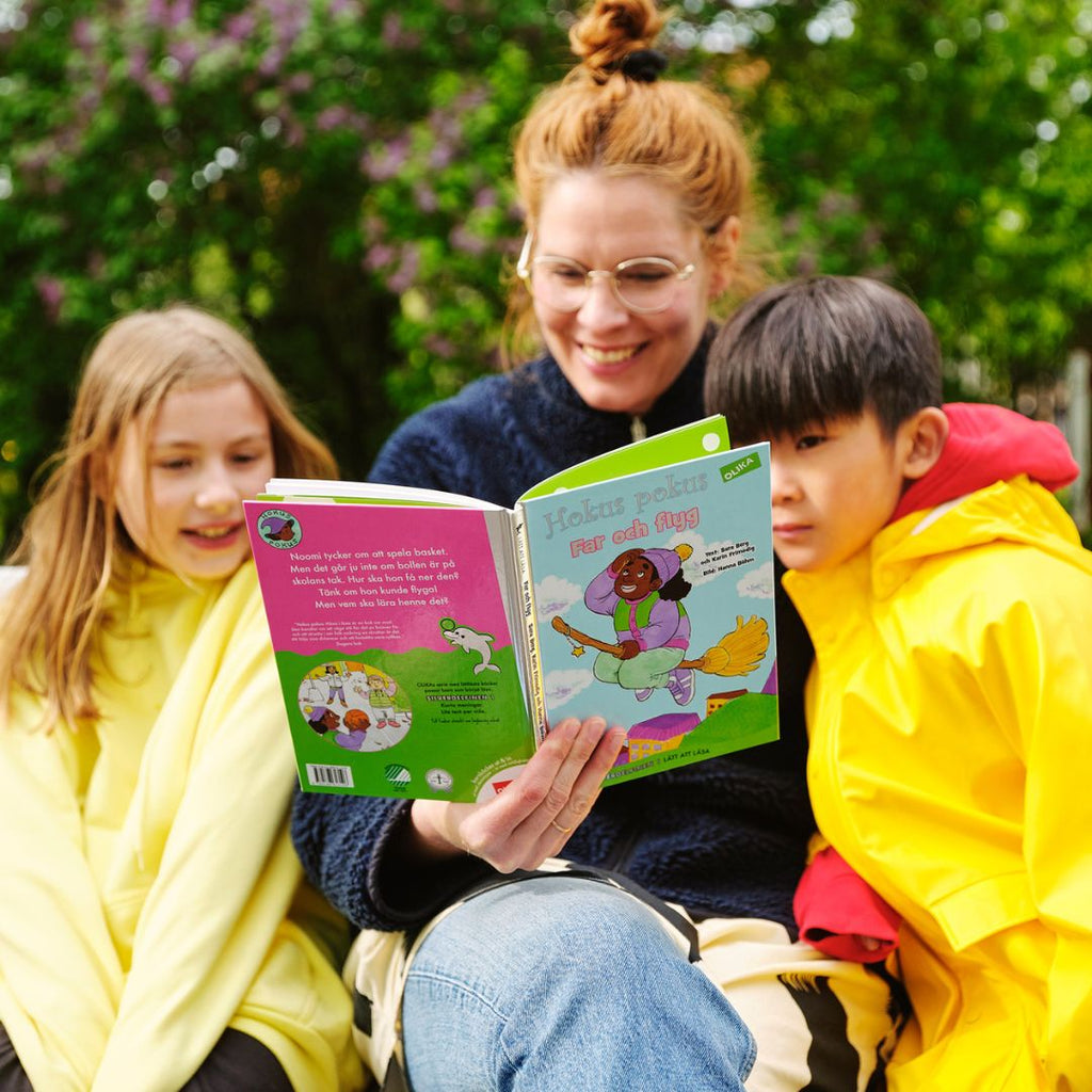 En vuxen och två barn läser Hokus pokus: Häxa i läxa.