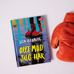 Kapitelboken Allt mod jag har på vit yta, till höger om boken ligger en rödorange boxningshandske