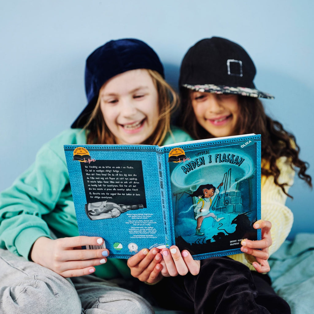 Två barn skrattar och läser tillsammans i Uppdrag: Anden i flaskan - Kapitelbok 6-9 år - OLIKA förlag - Författare: Cecilia Rihs - Illustratör: Jenny Lindqvist