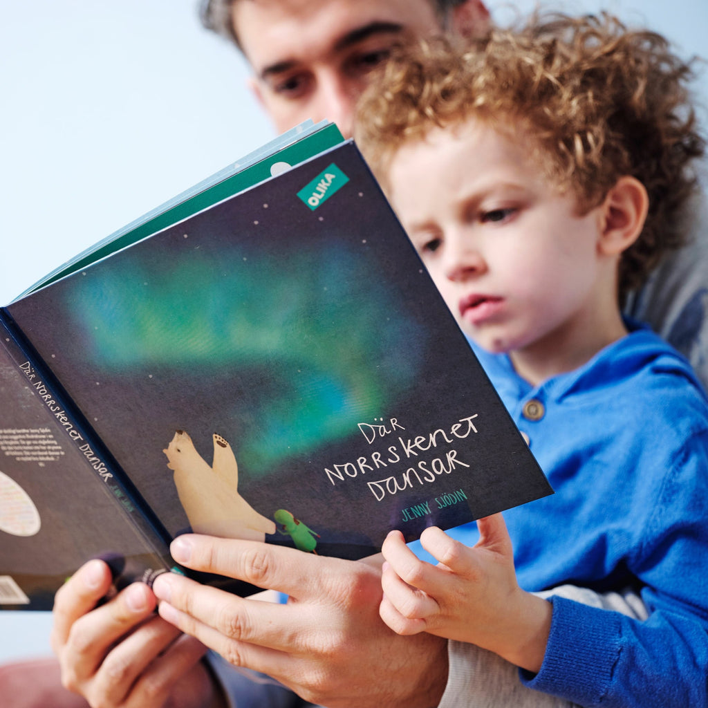 Förälder och barn sitter tillsammans och läser i Där norrskenet dansar - Bilderbok 3-6 år - OLIKA förlag - Författare: Jenny Sjödin - Illustratör: Jenny Sjödin