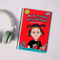 Lätt att läsa boken Du är en stjärna, Amy Jönsson! syns på vit yta. Bredvid boken ligger ett par mintgröna hörlurar