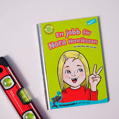 Lätt att läsa boken Ett jobb för Nora Henriksson syns på vit yta tillsammans med ett vattenpass