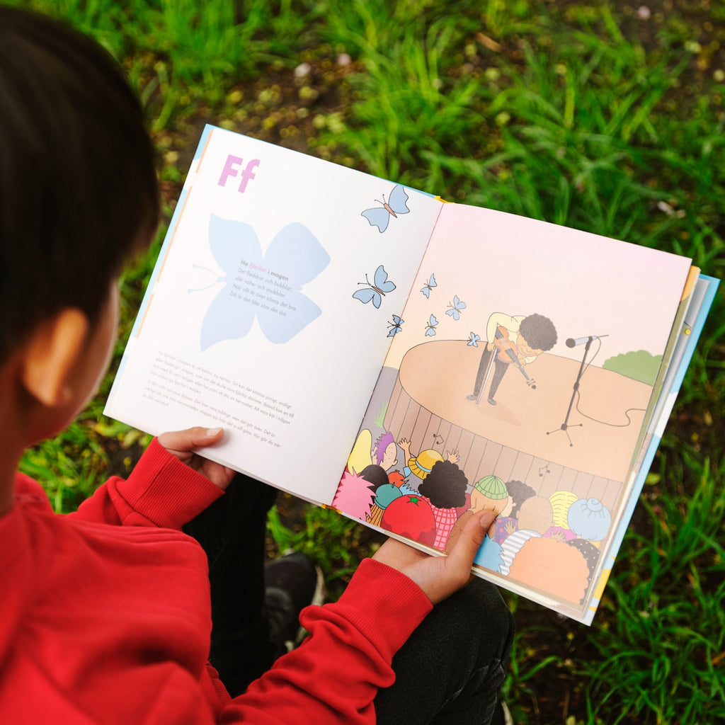 Ett barn tittar på illustrationerna i Fyndiga uttryckens ABC - Bilderbok 3-6 år - OLIKA - Författare: Mia Kim - Illustratör: Karin Holmström