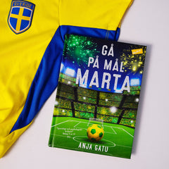 Kapitelboken Gå på mål, Marta ligger delvis på vit yta, delvis ovanpå en blågul fotbollströja