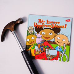 Bilderboken Här kommer UppfinnarJohanna! på vit yta, bredvid boken ligger en hammare
