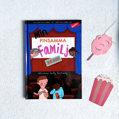 Lätt att läsa boken Min pinsamma familj på bio på vit träyta med en popcornhink och rosa sockervadd gjorda i papper