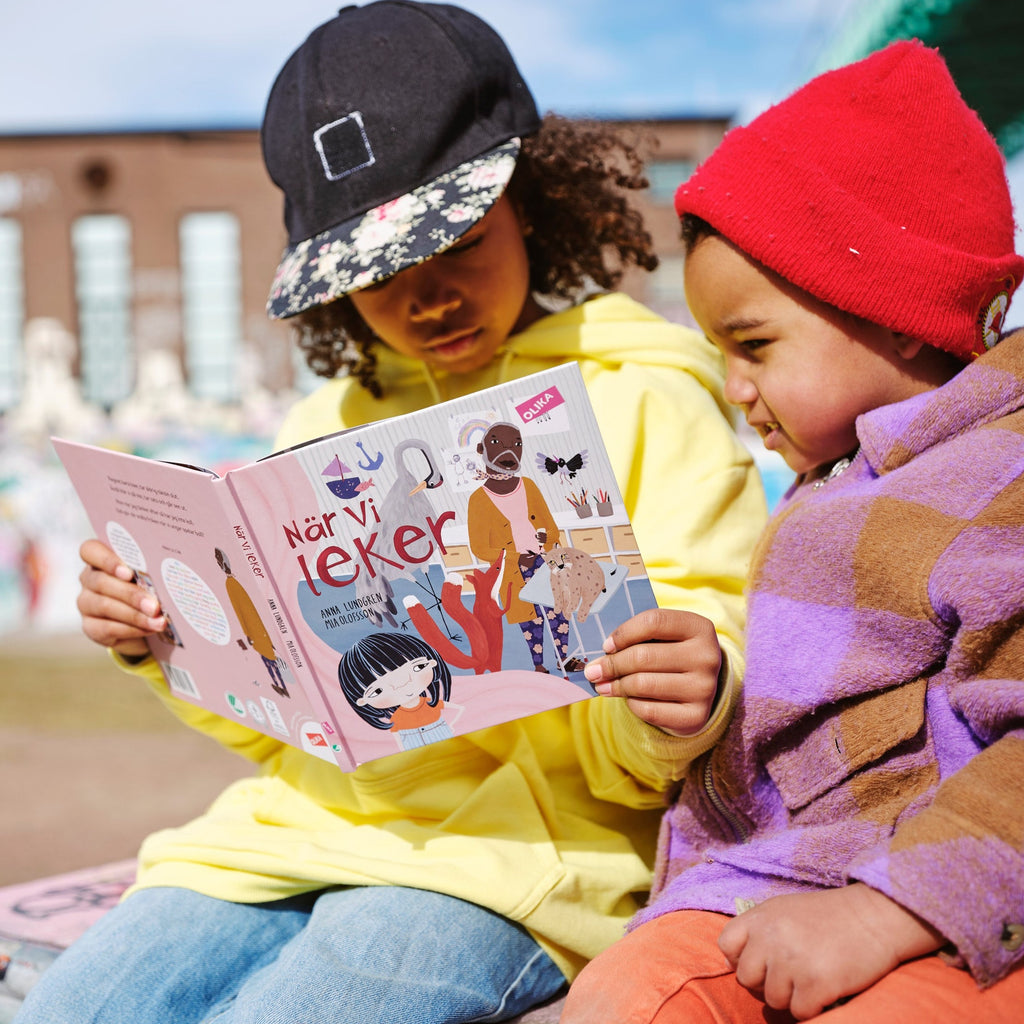 Två barn tittar tillsammans i en kopia av När vi leker - Bilderbok 1-3 år - OLIKA förlag - Författare: Anna Lundgren - Illustratör: Mia Olofsson