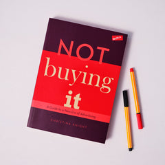 Metodboken Not buying it på vit yta tillsammans med några pennor