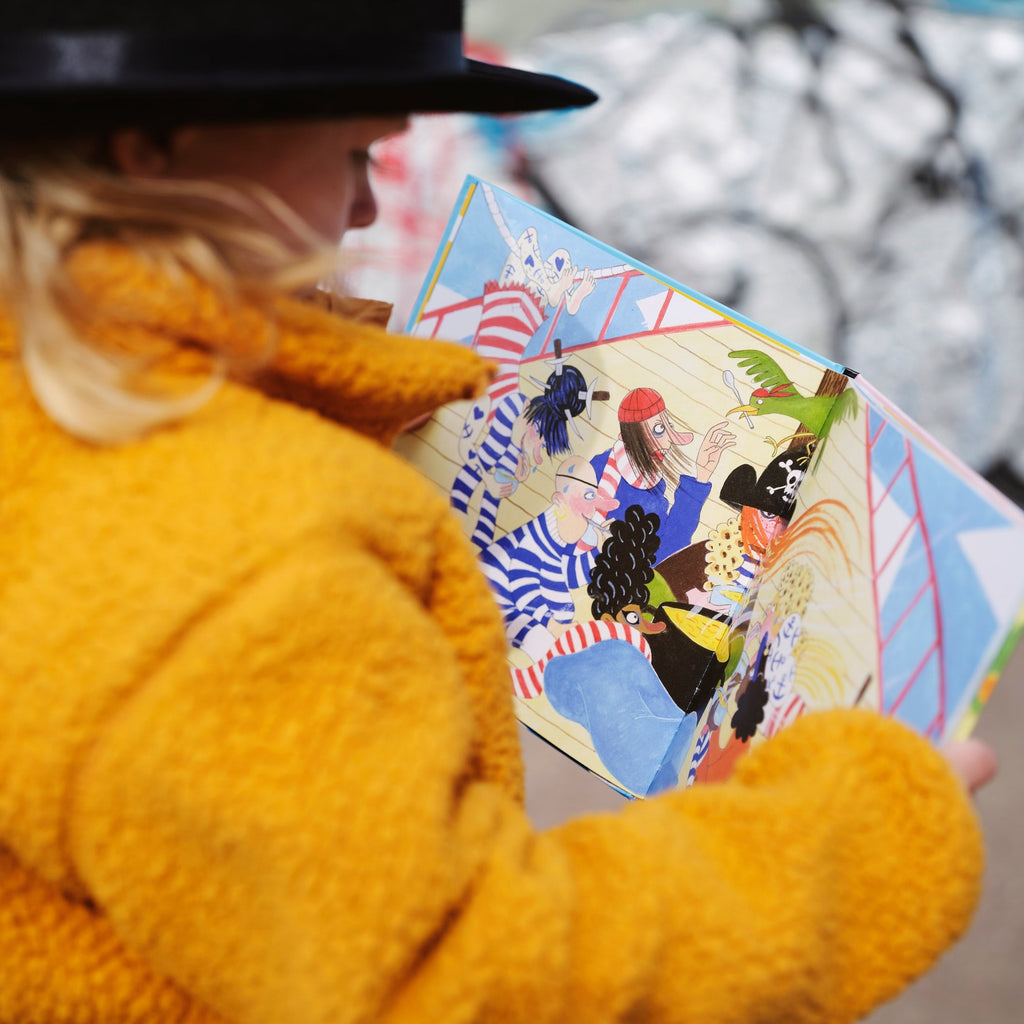 Ett barn tittar på en illustrerad bild av kvinnliga pirater i Piraterna & vinterjakten - Bilderbok 3-6 år - OLIKA förlag - Författare: Karin Frimodig och Sara Berg - Illustratör: Maria Poll