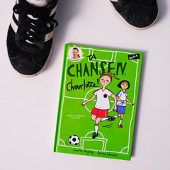 Kapitelboken Ta chansen, Charlotte! syns på vit yta med ett par fotbollsskor