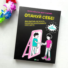Metodboken Opanui sebe (Ta makten 1 på ukrainska) 13+ på vit träyta. I övre vänstra hörnet, en färgglad blomsterkrans