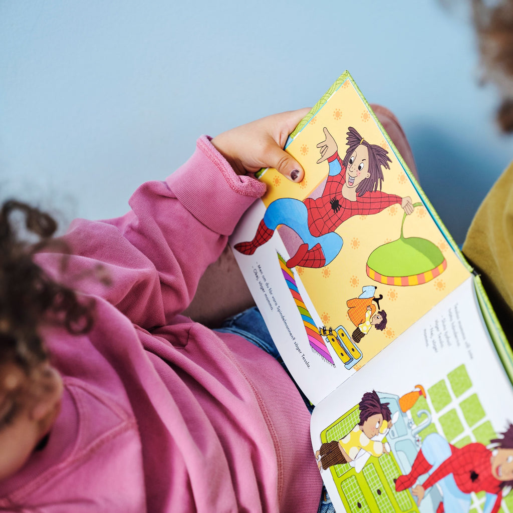 Ett barn i rosa tröja läser Tesslas mamma vill inte! - Bilderbok 1-3 år - OLIKA förlag - Författare: Åsa Mendel Hartvig - Illustratör: Caroline Röstlund