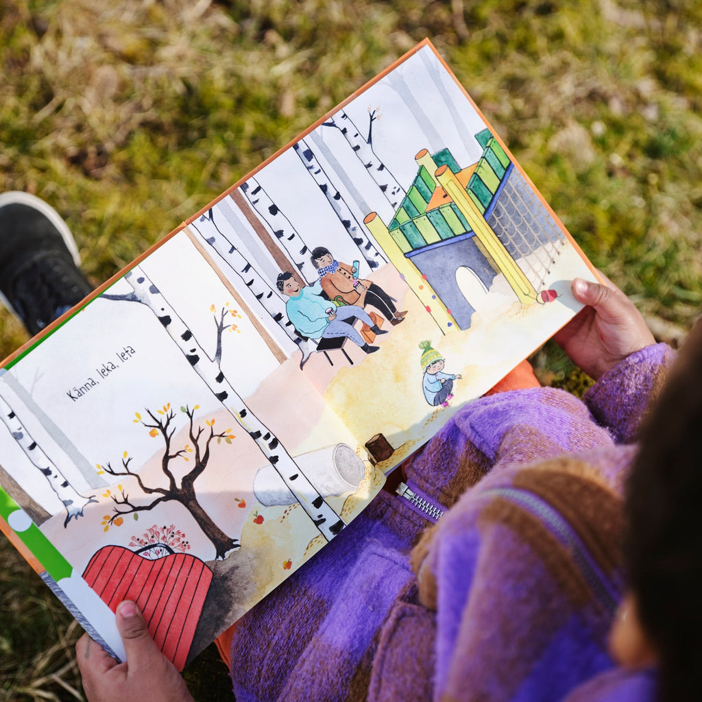 Ett barn i lila jacka tittar på illustrationerna i Zozo och hunden - Bilderbok 1-3 år - OLIKA förlag - Författare: Elina Garp - Illustratör: Moa Graaf